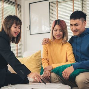 Happy young Asian couple and realtor agent.